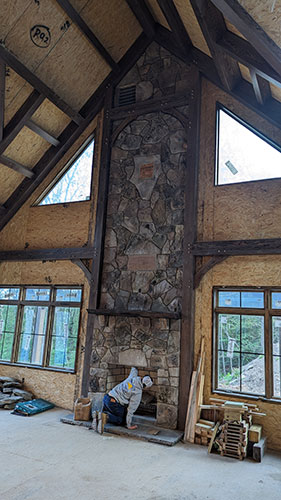 A room with a stone fireplace and windows